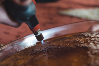 Close-up of man preparing creme brulee with flambe