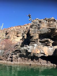 View of rocks in water against clear blue sky