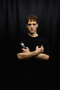 Portrait of young man exercising against black background