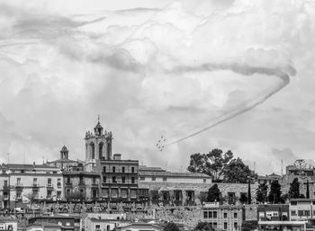 Buildings in city against cloudy sky