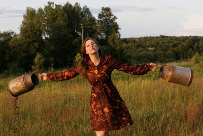 Woman holding container while standing against sky