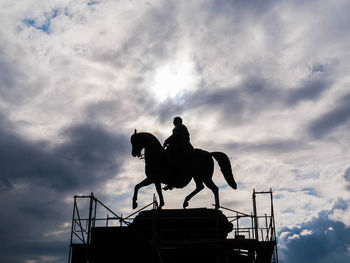 Low angle view of silhouette horse riding against sky