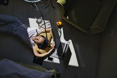 Young woman lying at the window at home with laptop