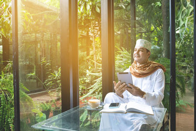 Man looking at camera while sitting by window