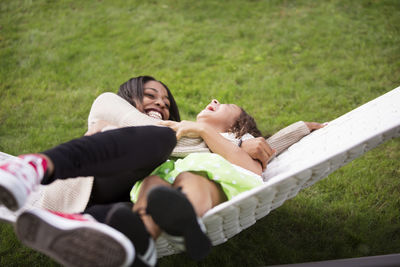Happy sisters lying in hammock at backyard