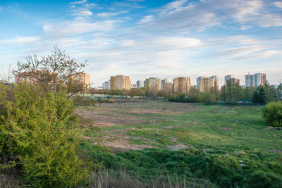 Scenic view of field by buildings against sky