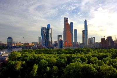 Trees and buildings in city against sky