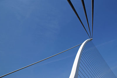 Low angle view of suspension bridge against clear blue sky