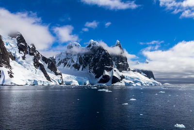 Scenic view of sea and snowcapped mountains against sky