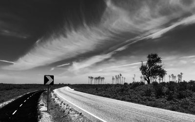 Road amidst field against sky