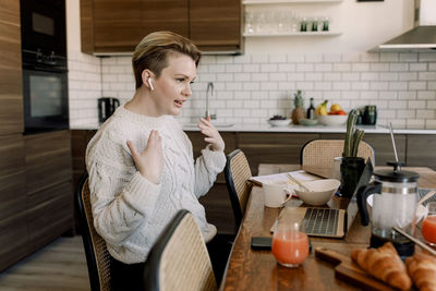 Lesbian professional gesturing while doing video call through laptop on dining table at home