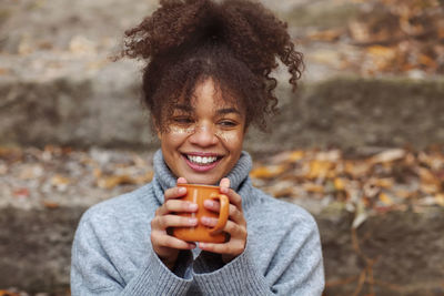 Portrait of young woman with mug outdoors