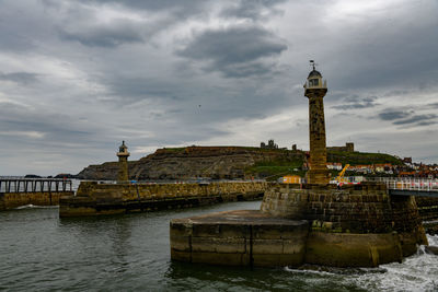 View of old building by river against cloudy sky