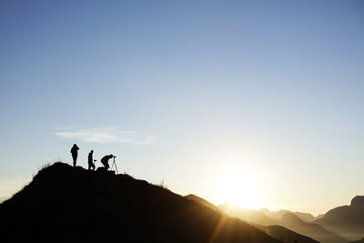 Silhouette people standing on mountain against sky during sunset