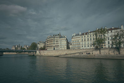 Bridge over river by buildings in city against sky