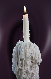 Close-up of burning candle against black background