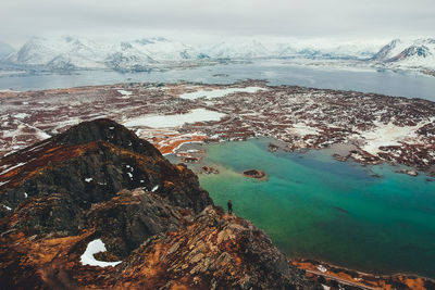 Aerial view of man standing on rock against lake and mountains