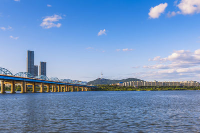 View of city at waterfront against cloudy sky