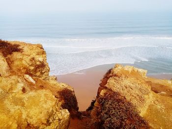 Rock formation on beach against sky