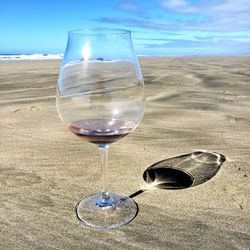 Close-up of wine glass on beach