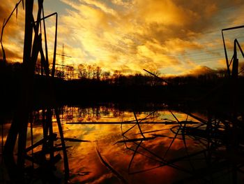 Silhouette trees against dramatic sky during sunset