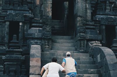 Rear view of men outside temple against building