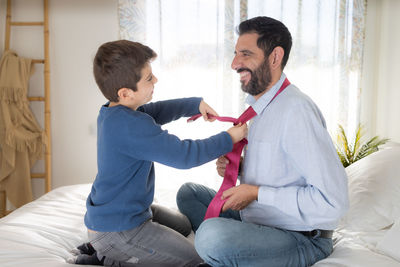 Son helping his father put on his necktie