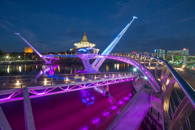 Illuminated bridge over river at night