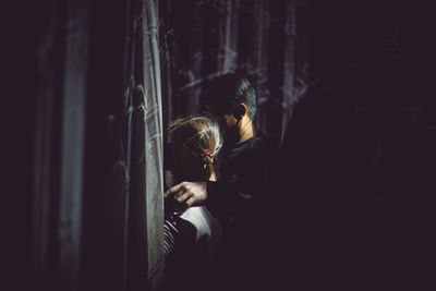 Rear view of man and woman standing in dark