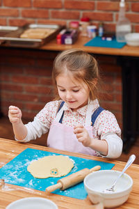 High angle view of cute girl making cookies on table at home
