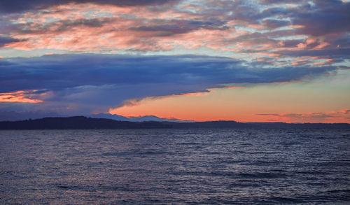 Scenic view of sea against dramatic sky during sunset