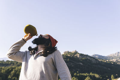 Bearded man drinking water on sunny day