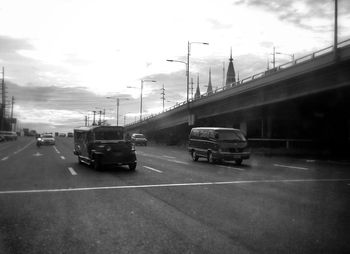 Cars on road against cloudy sky