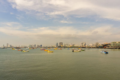 Sailboats in sea against buildings in city