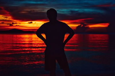 Silhouette man looking at sea against sky during sunset