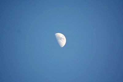 Low angle view of moon against clear blue sky