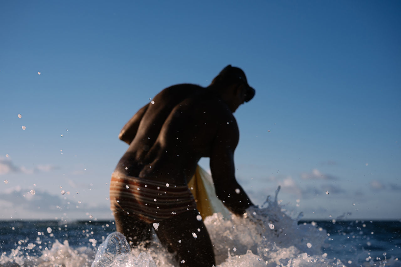 MAN PLAYING AT SEA AGAINST CLEAR BLUE SKY