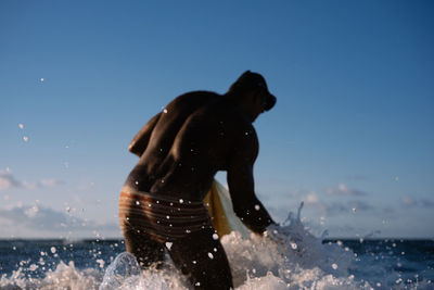 Man playing in sea against clear blue sky