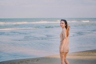 Portrait of smiling young woman standing at beach