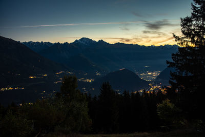 Silhouette trees by mountains against sky during sunset