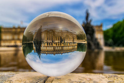 Close-up of crystal ball on water against sky