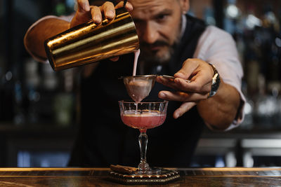 Midsection of man pouring wine in glass