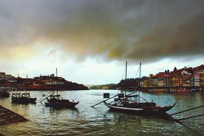 Boats in harbor against cloudy sky