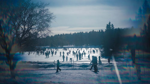 Group of people on snow covered landscape against sky