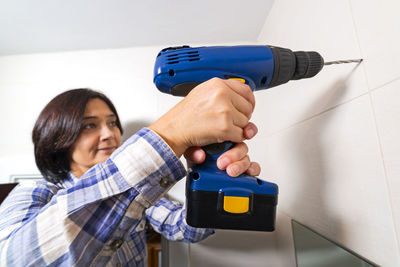 Woman drilling wall at home