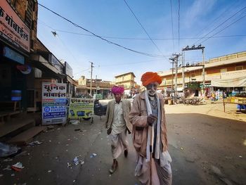 People walking on street in city against sky