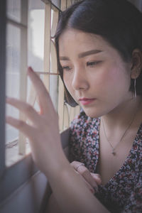 Close-up of thoughtful young woman looking through window