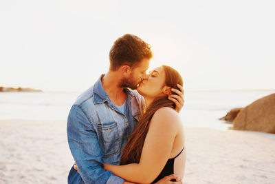 Young couple on beach against sky