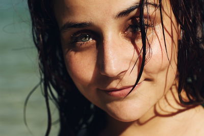 Close-up portrait of smiling young woman with wet hair