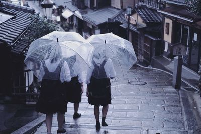 Rear view of people walking on wet street during rainy season